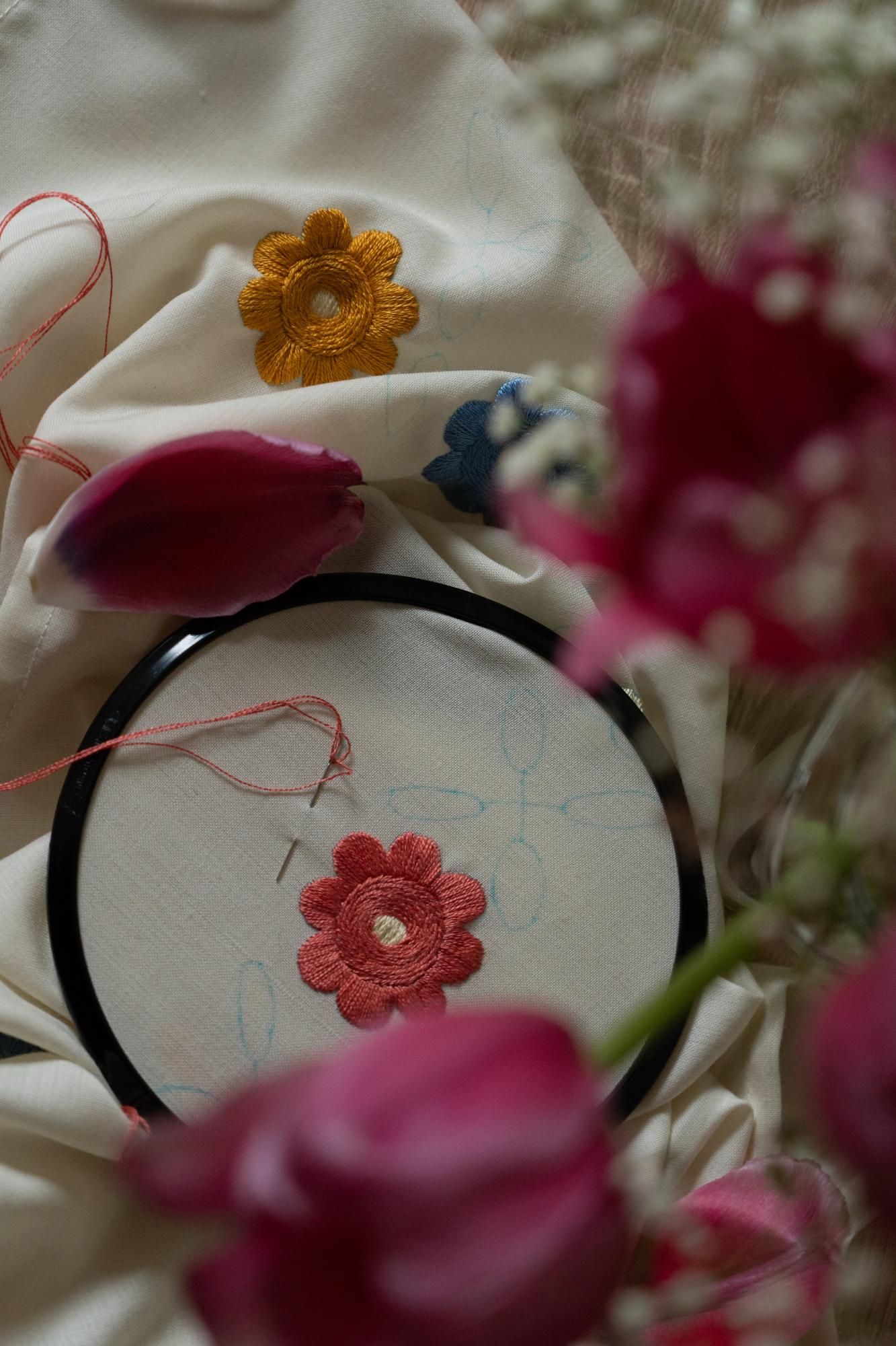 Close-up of artisan hand embroidering a floral motif on linen